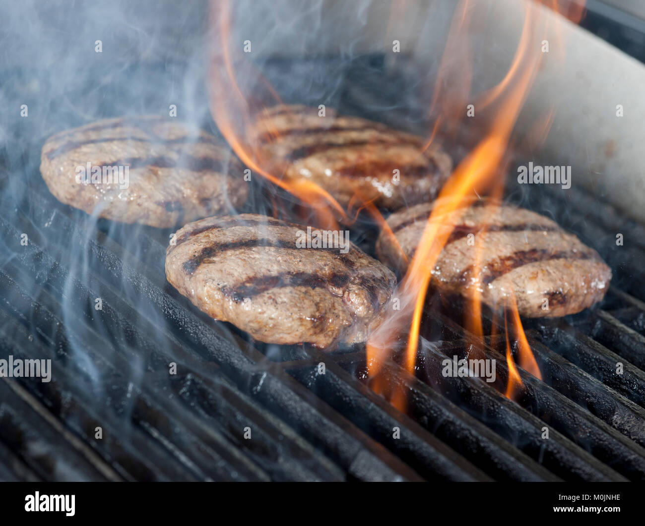 Burger de viande de poulet quatre steaks sur le grill avec des flammes. la cuisson du poulet sur le gril ou barbecue ou barbecue à charbon. Close up Banque D'Images