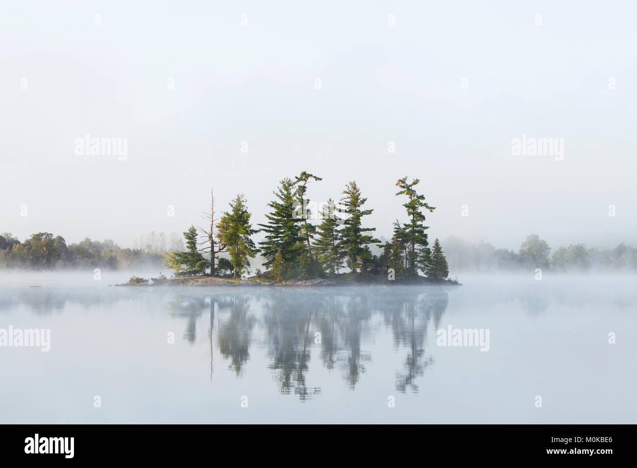Le brouillard entoure une petite île sur le lac de tortues dans la région de Muskoka (Ontario), près de Rosseau ; Ontario, Canada Banque D'Images