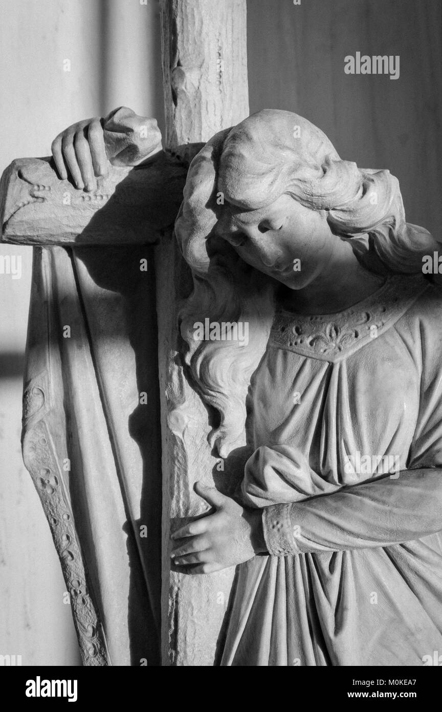 Statue d'un ange pur tenant une croix avec les yeux fermés, photo en noir et blanc Banque D'Images