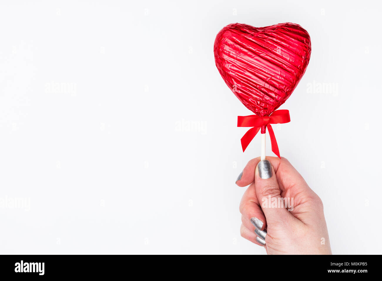 Cadeaux de la Saint-Valentin. Femme main tenant une sucette en forme de coeur Banque D'Images