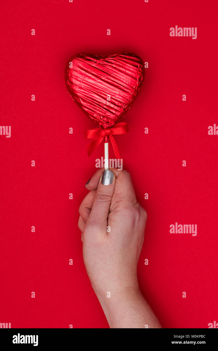Cadeaux de la Saint-Valentin. Femme tenant une main en forme de coeur sur fond rouge loll Banque D'Images