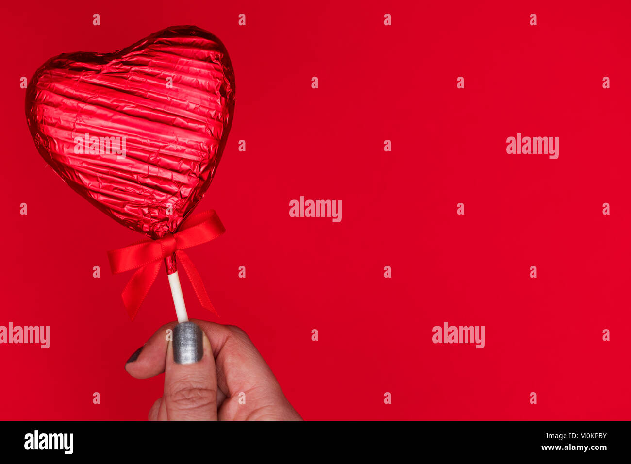 Cadeaux de la Saint-Valentin. Femme tenant une main en forme de coeur sur fond rouge loll Banque D'Images