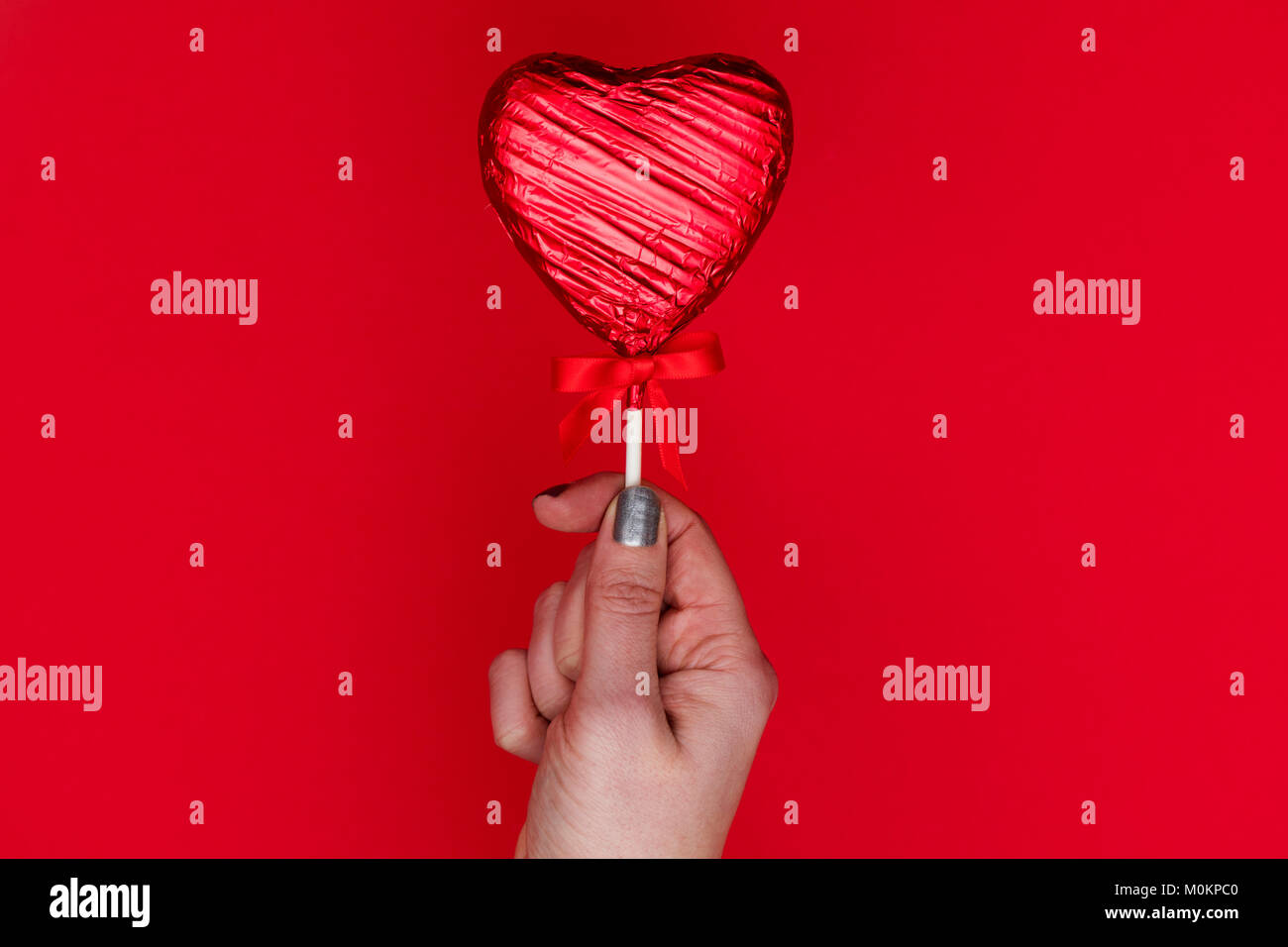 Cadeaux de la Saint-Valentin. Femme tenant une main en forme de coeur sur fond rouge loll Banque D'Images