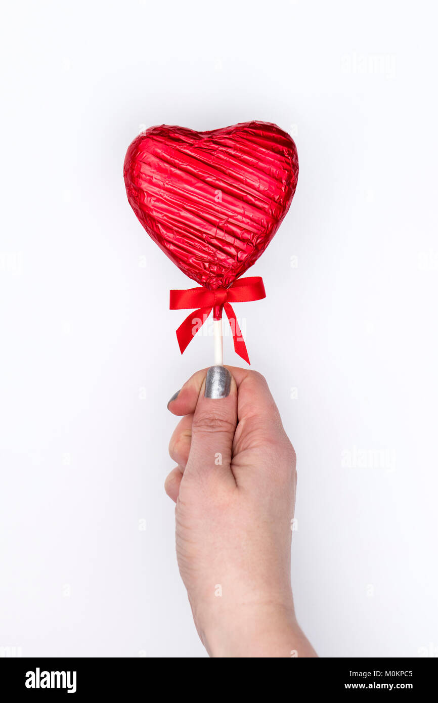 Cadeaux de la Saint-Valentin. Femme main tenant une sucette en forme de coeur Banque D'Images