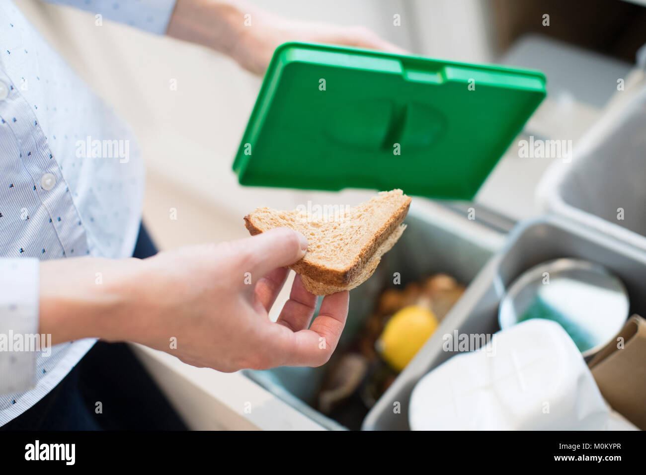 Près de la femme mettre des aliments les déchets en bac de recyclage dans la cuisine Banque D'Images