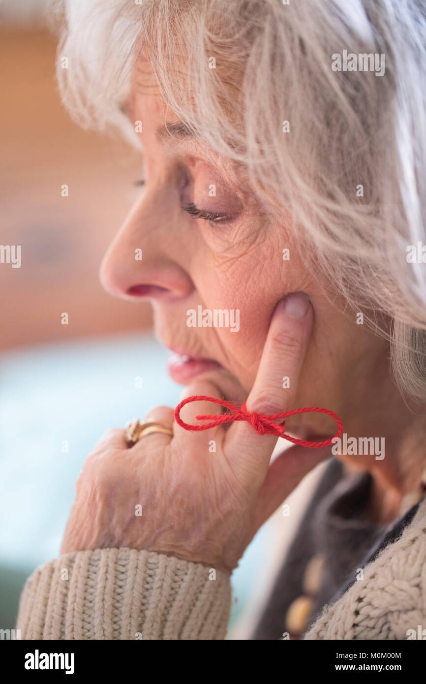 Close Up of Senior Woman with String attaché autour du doigt comme rappel Banque D'Images