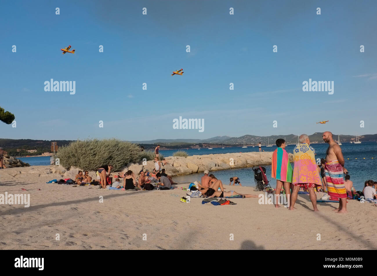 Les gens sur une plage de La Ciotat, France alors que les avions de lutte contre l'incendie. Banque D'Images