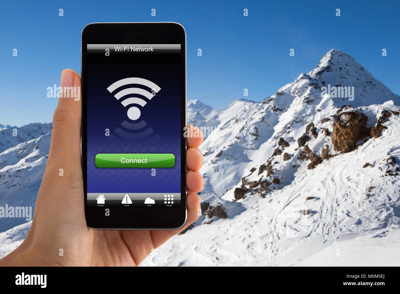 Close-up of Hand Holding Mobile Phone avec signal Wi-fi dans la Montagne enneigée Banque D'Images