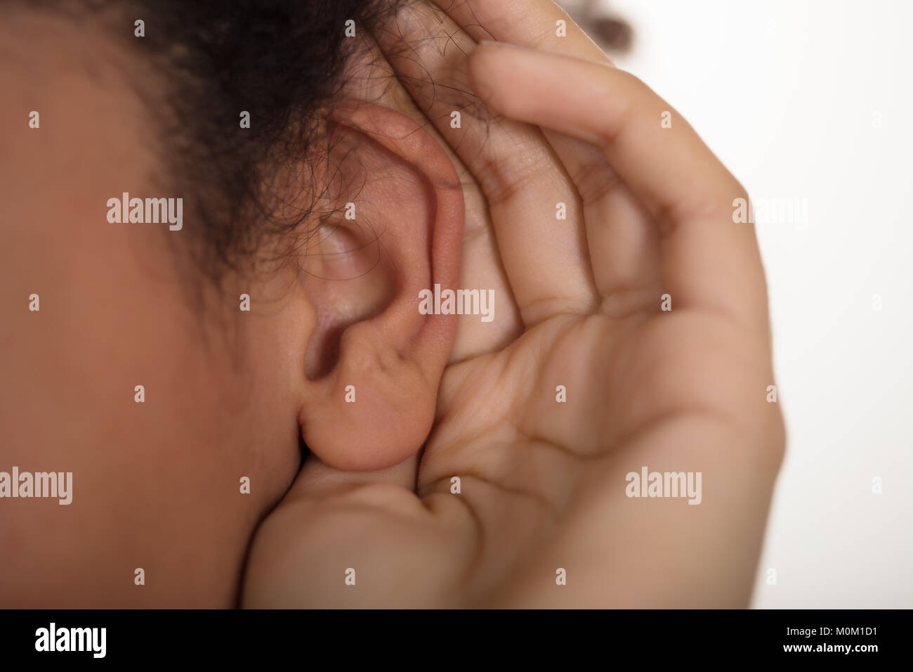 Close-up of personne essaie d'écouter avec l'oreille de la main Banque D'Images