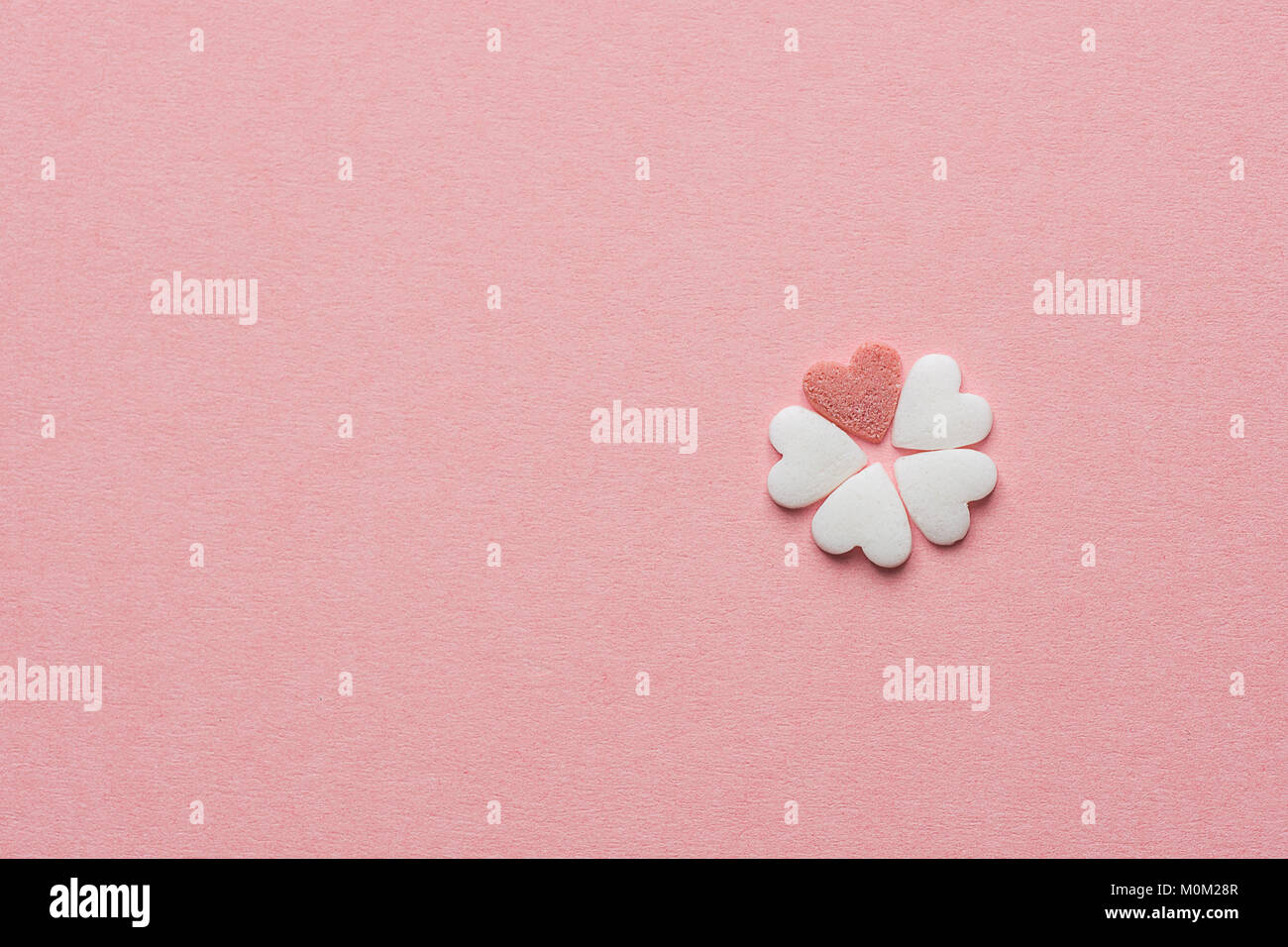 Petite jolie fleur faite de sucre en forme de coeur rouge et blanc Candy Sprinkles sur fond rose pastel. Saint Valentin Fête des mères enfants la créativité de bienfaisance Banque D'Images