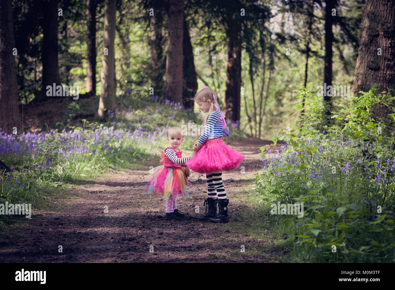 Deux enfants en robes colorées, sur un chemin forestiers Banque D'Images
