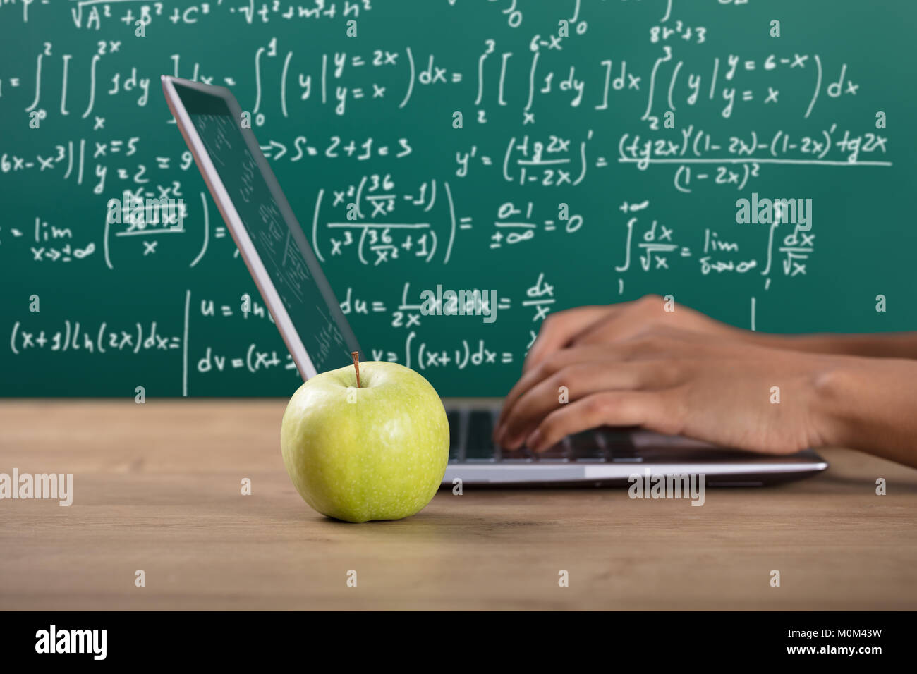 Close-up d'une main à l'aide d'ordinateur portable près de Green Apple en classe Banque D'Images