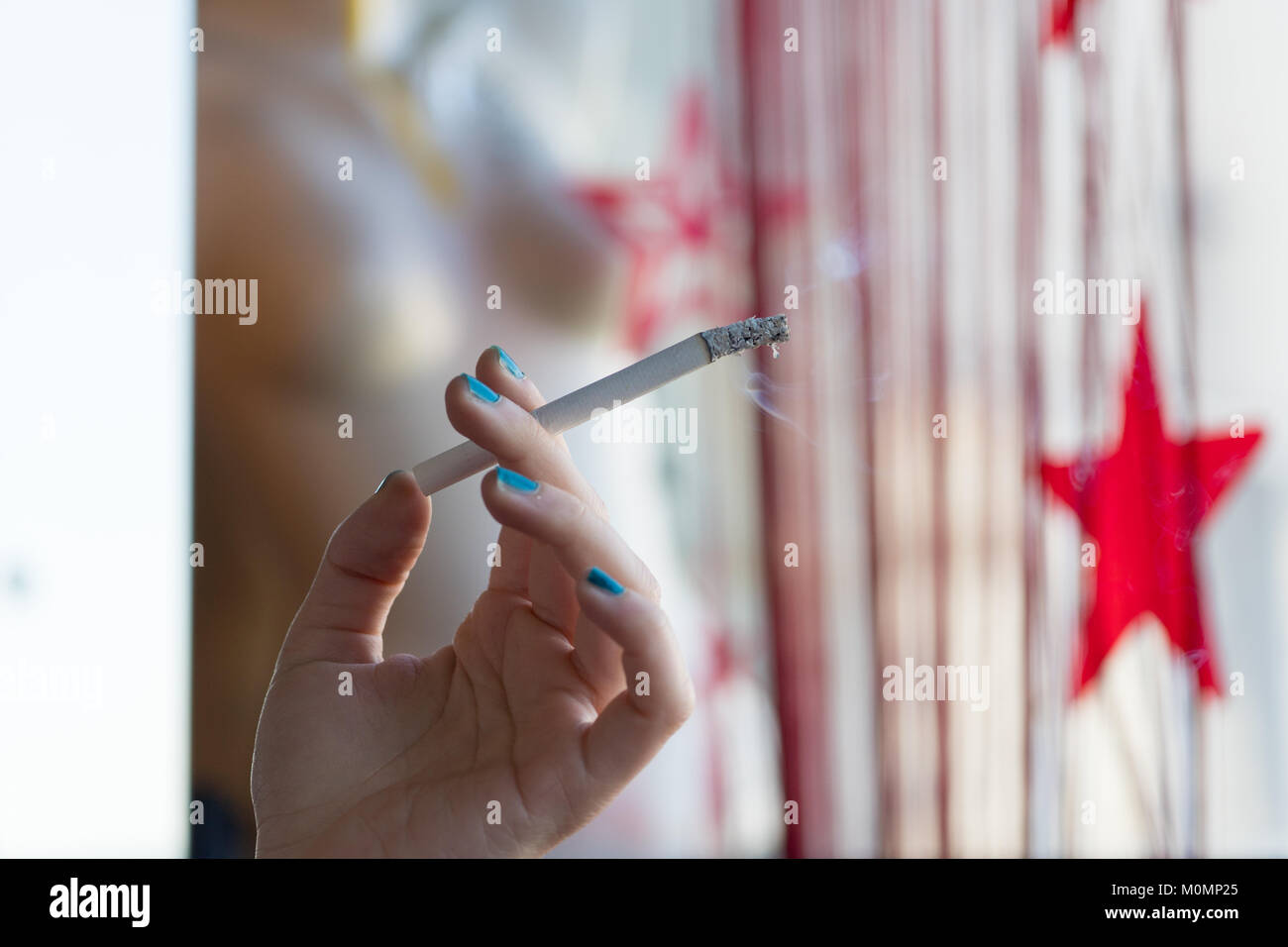 Femme tenant une cigarette à la main avec de la fumée Banque D'Images
