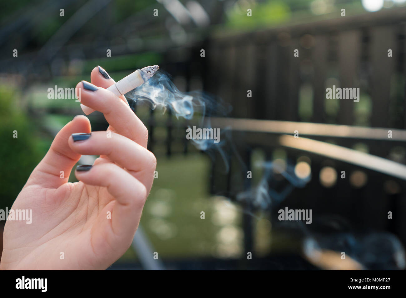 Femme tenant une cigarette à la main avec de la fumée Banque D'Images