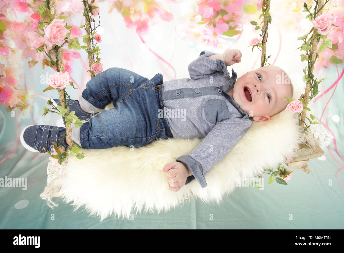 Baby Boy laughing on toy swing Banque D'Images