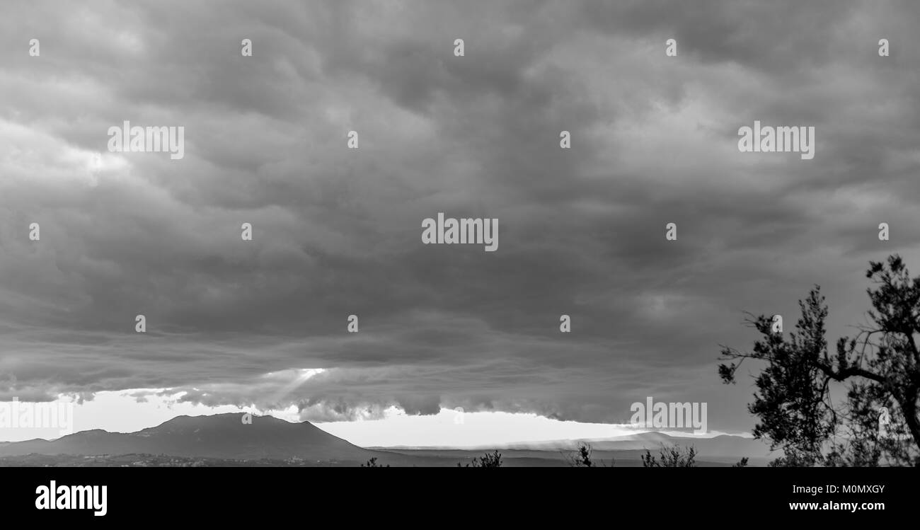 Tempête arrivant avec des nuages gris, les rayons du soleil frappant de montagne dans l'arrière-plan et d'oliviers au premier plan. Poggio Mirteto, lazio, Italie. Fe Banque D'Images
