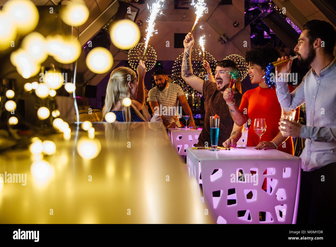 Groupe d'amis font la fête dans une discothèque avec piscine cierges et des boissons alcoolisées. Banque D'Images