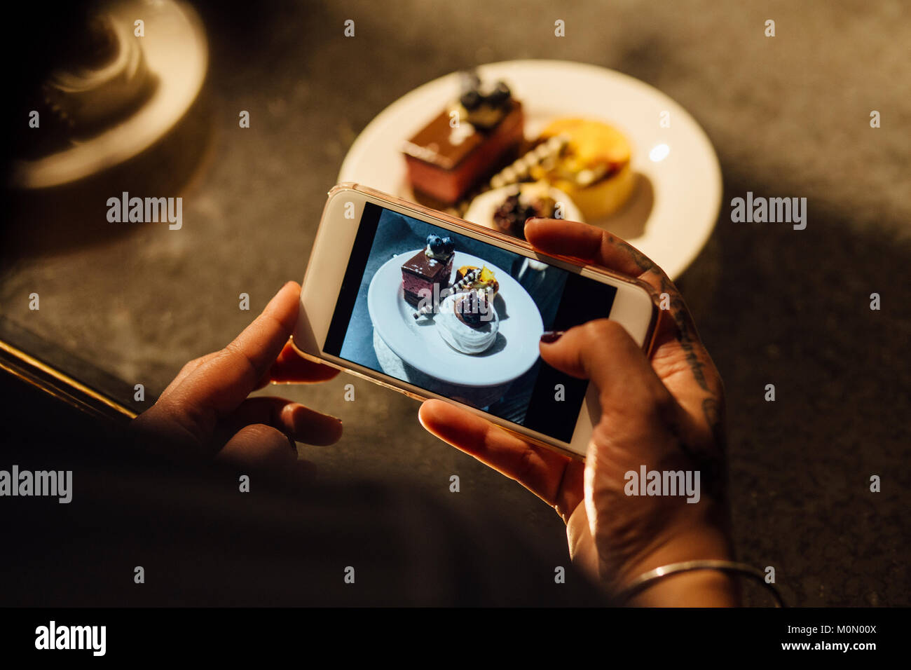 Femme utilise son téléphone pour prendre une photo d'un plateau de thé de l'après-midi. Banque D'Images