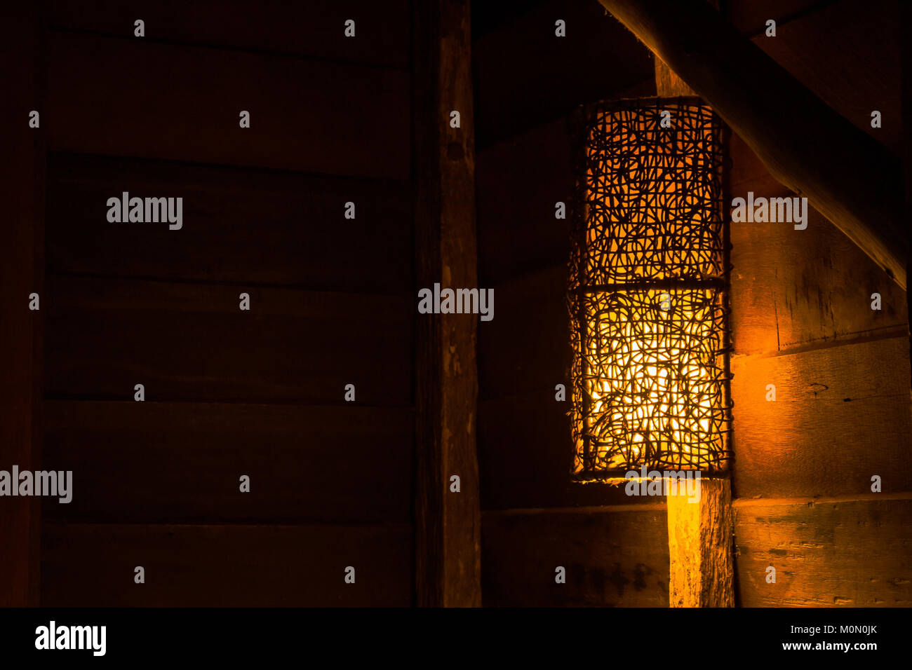 Belle lampe murale en bois sur bois suspendu au-dessus du lit le journal dans le chalet de campagne. Banque D'Images