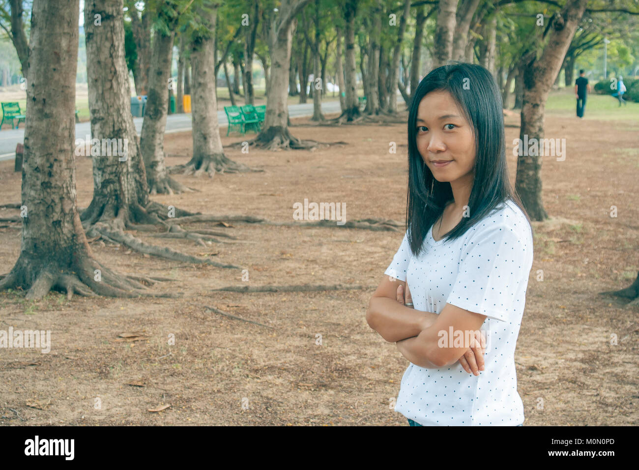 Woman wearing white t-shirt, elle debout sur l'herbe verte dans le parc et de sourire. Banque D'Images