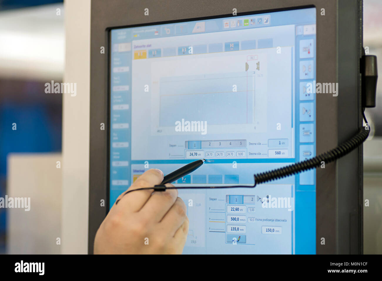 La main avec un stylo sur une console avec écran tactile pour contrôler une machine industrielle dans une usine Banque D'Images
