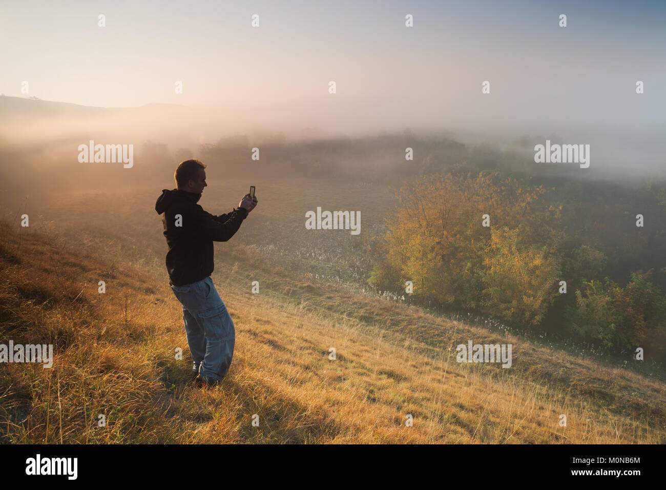 L'homme est la randonnée et photographier la nature avec téléphone mobile dans la matinée. Banque D'Images