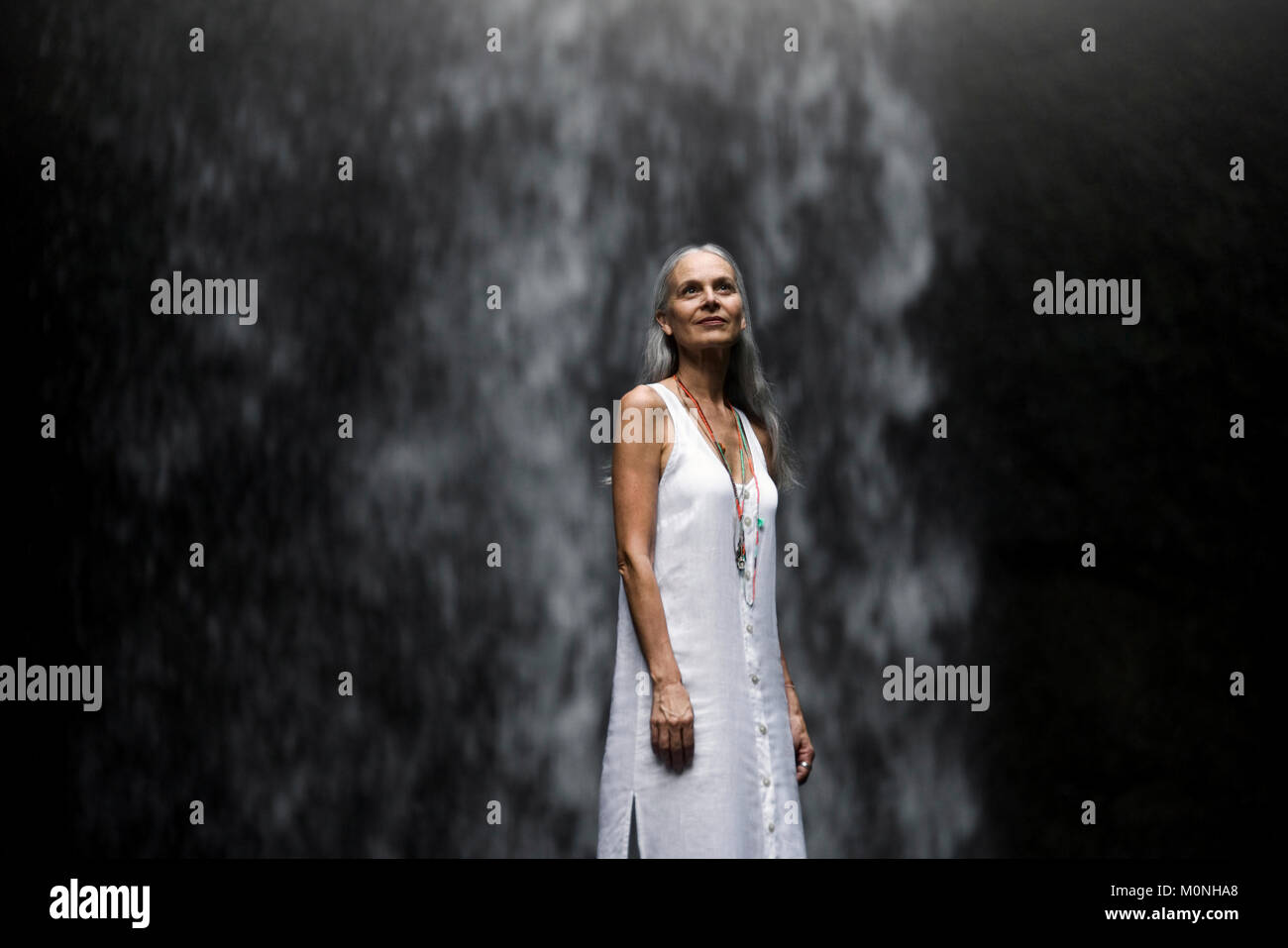 Belle senior woman standing in front of a cascade tropicale Banque D'Images Belle senior woman standing in front of a cascade tropicale Banque D'Images