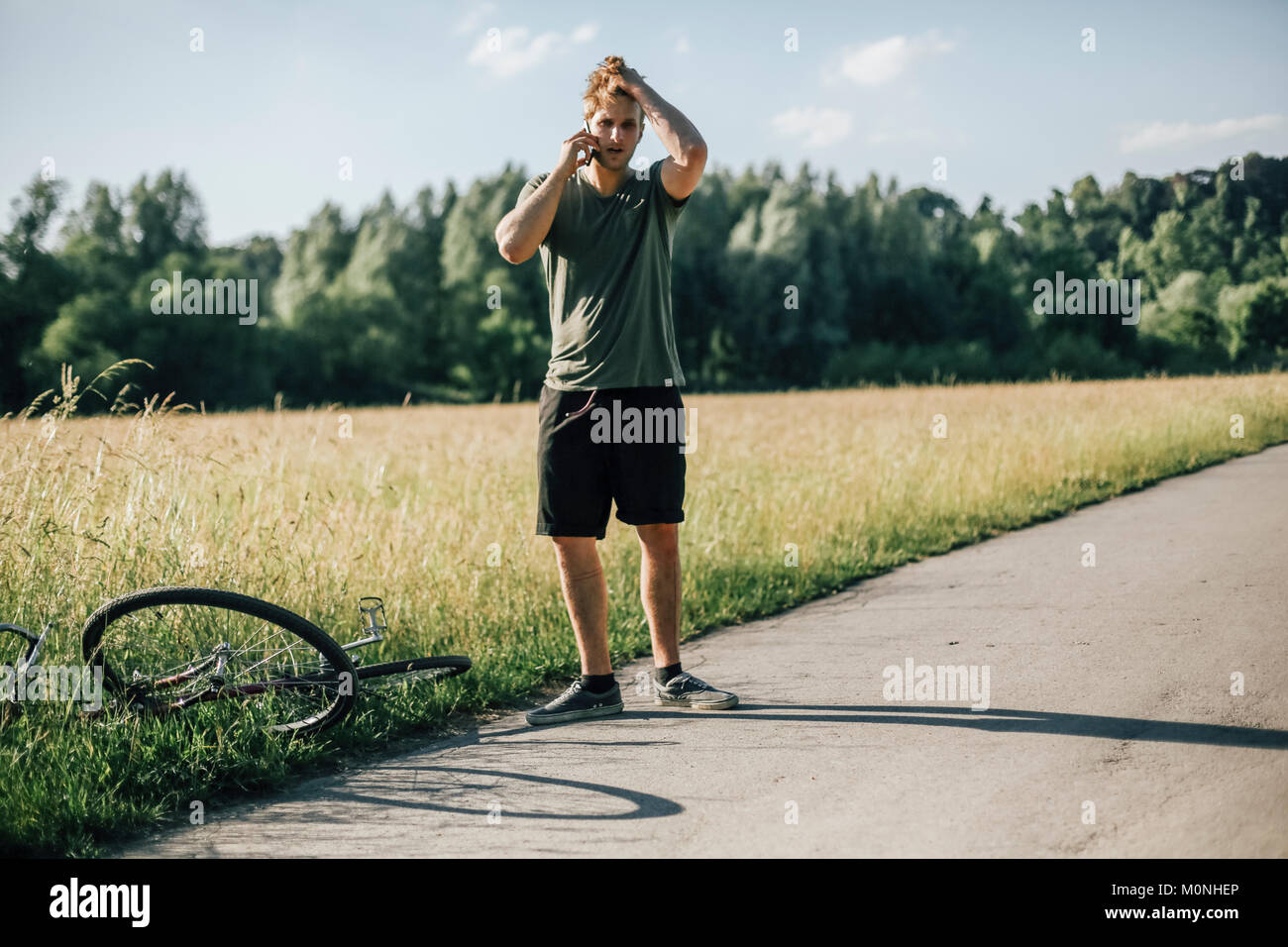 Jeune homme au téléphone, tour en vélo, d'un accident Banque D'Images Jeune homme au téléphone, tour en vélo, d'un accident Banque D'Images