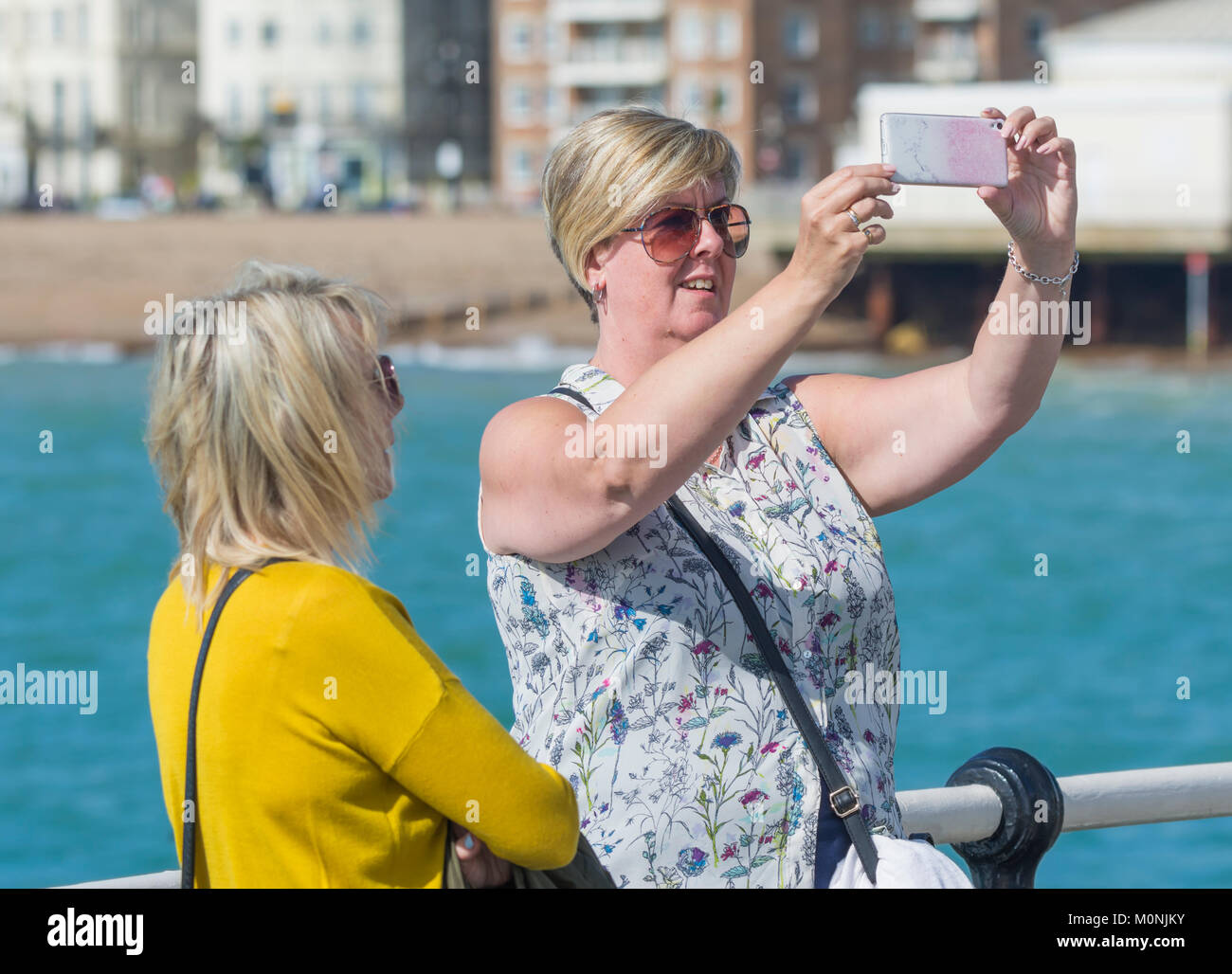 Un couple d'amies à la mer en tenant vos autoportraits sur un smartphone au Royaume-Uni. Banque D'Images Un couple d'amies à la mer en tenant vos autoportraits sur un smartphone au Royaume-Uni. Banque D'Images