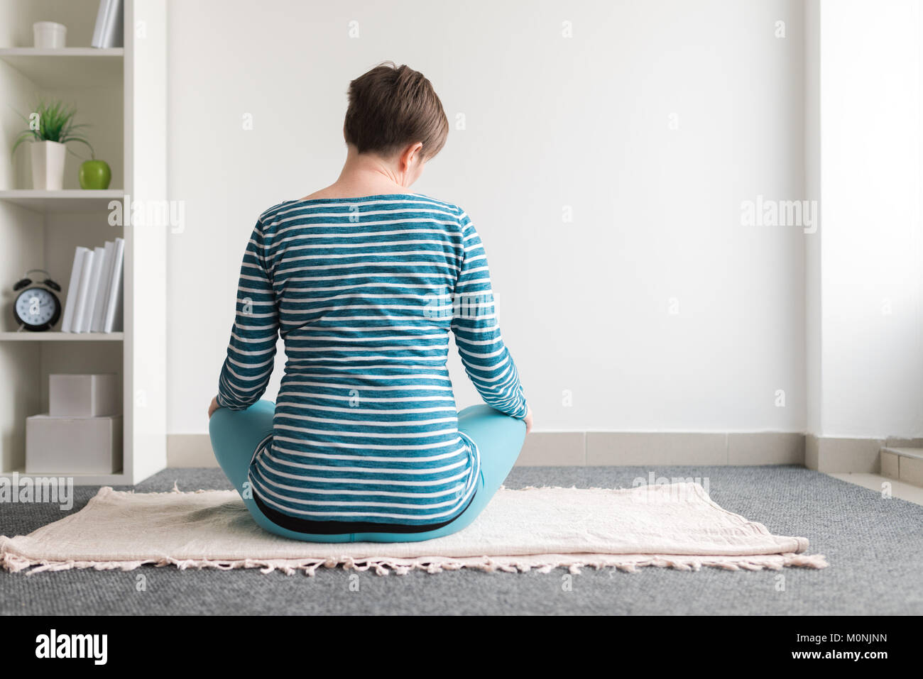 Pregnant woman practicing yoga exercice à la maison. Le yoga et la grossesse à l'intérieur concept de remise en forme. Images à faible contraste hors cadre naturel avec la lumière de la fenêtre. Banque D'Images