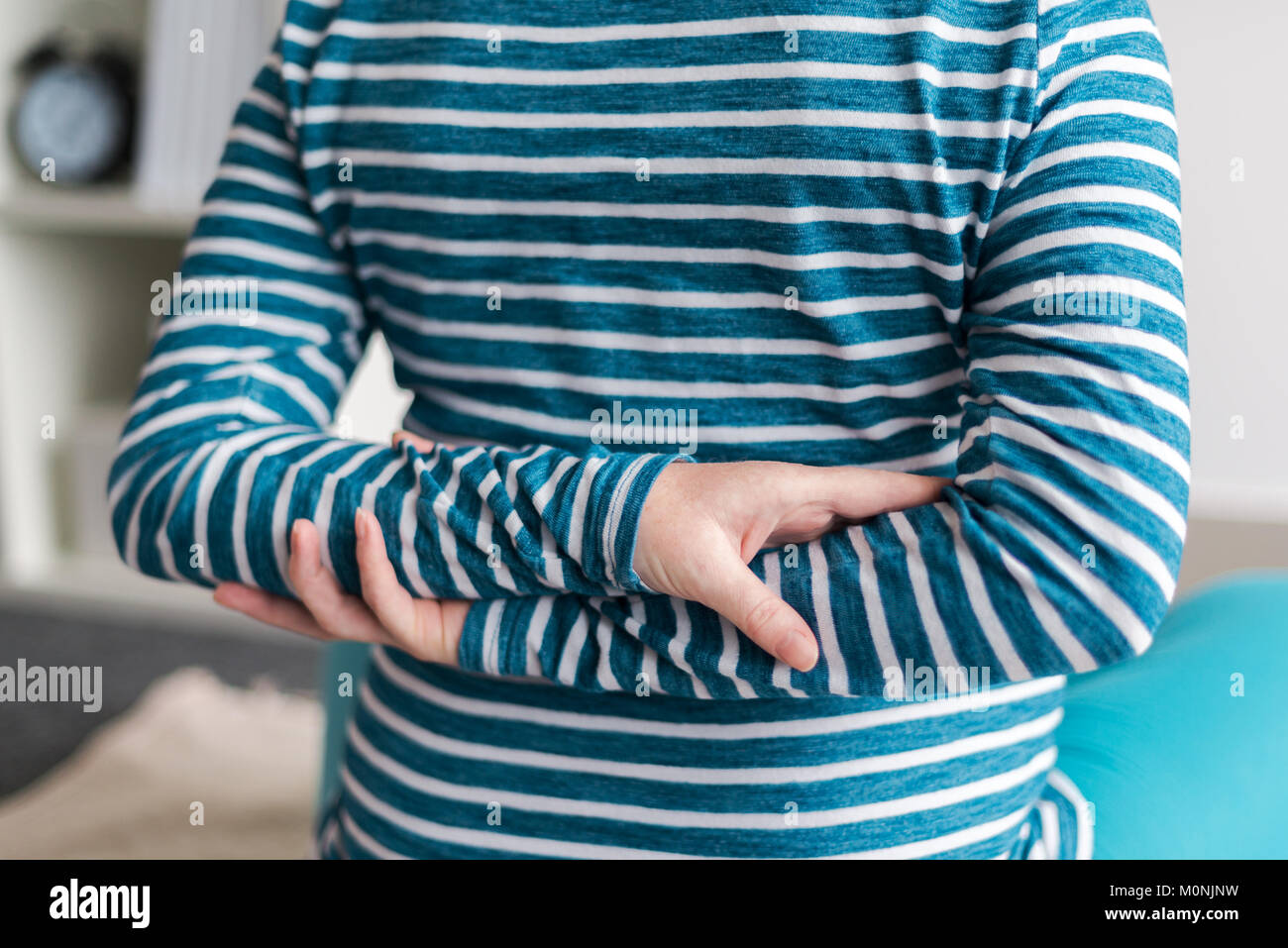Pregnant woman practicing yoga exercice à la maison. Le yoga et la grossesse à l'intérieur concept de remise en forme. Images à faible contraste hors cadre naturel avec la lumière de la fenêtre. Banque D'Images
