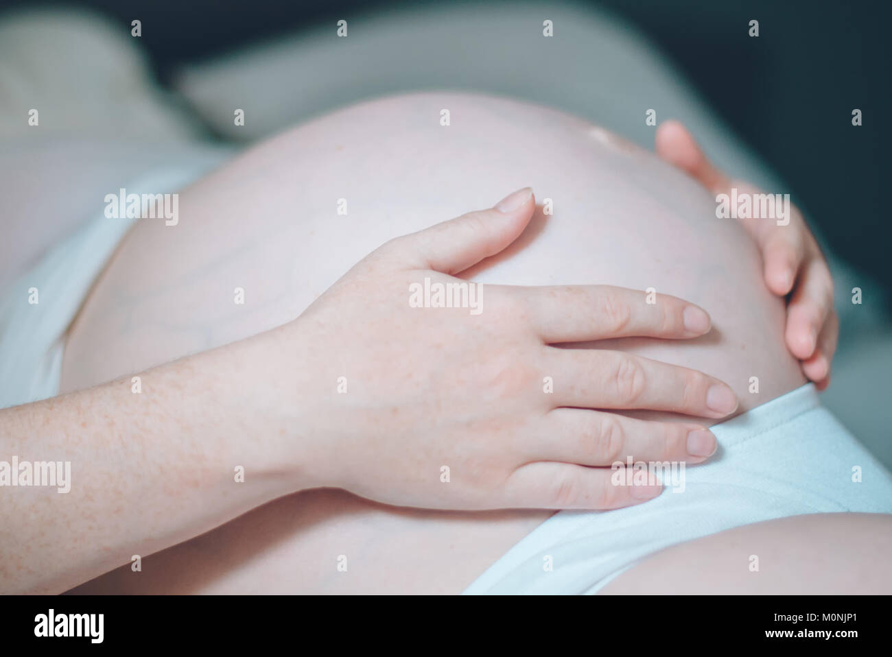 Femme enceinte ventre câlins dans la chambre à la maison juste avant le travail et l'accouchement, selective focus Banque D'Images