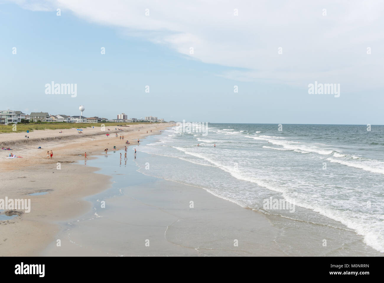 En regardant vers l'horizon les vagues déferlent sur la plage de sable fin que les gens profiter de la journée d'été, Wilmington, Caroline du Nord. Banque D'Images