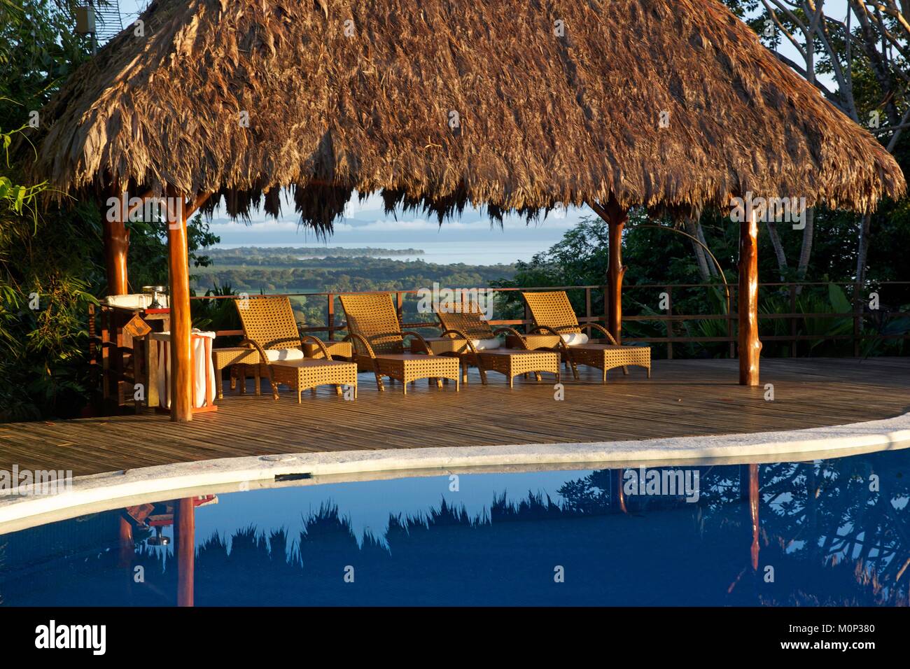Costa Rica, Osa peninsula,transats alignés au bord de la piscine de l'ecolodge Lapa Rios sous un pavillon avec toit vert,donnant sur l'océan Banque D'Images