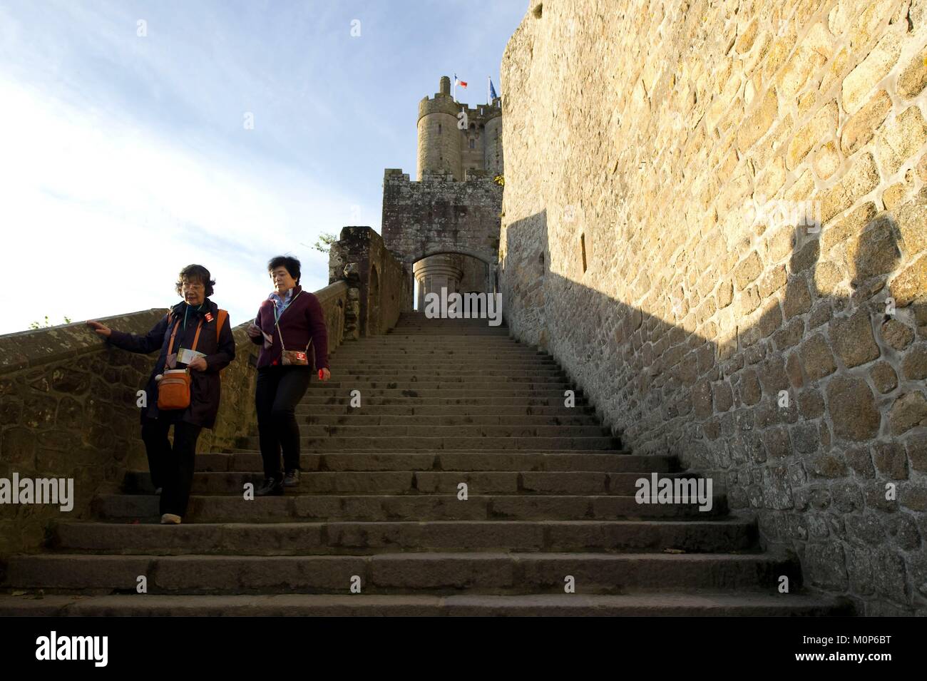 France,Manche,Baie du Mont Saint Michel classé au Patrimoine Mondial par l'UNESCO, le Mont Saint Michel,deux touristes asiatiques en descendant les escaliers pour guider l'abbaye Banque D'Images