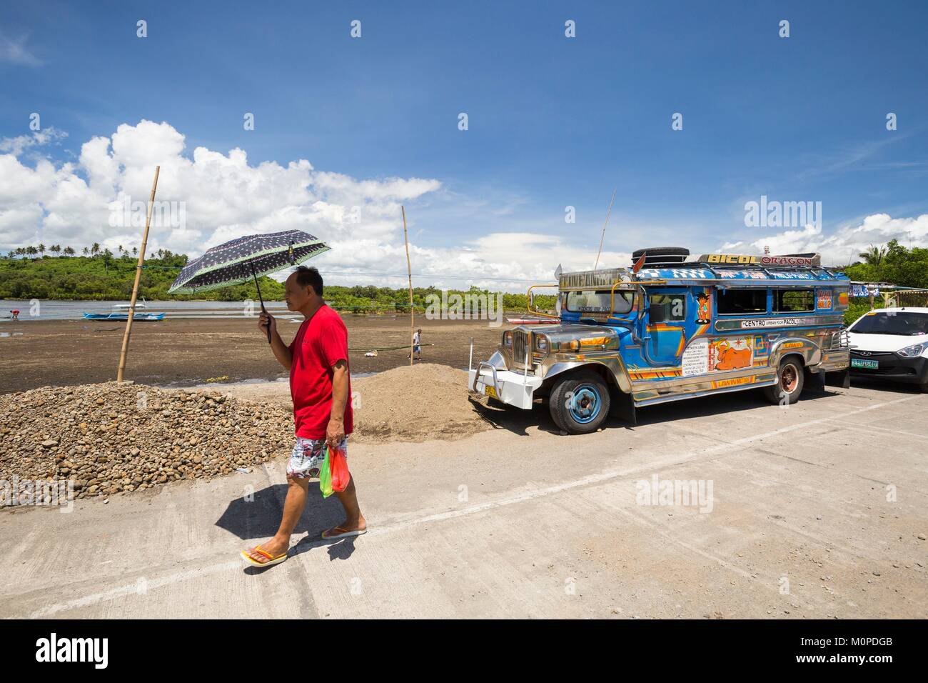 Philippines,Luzon, Camarines Sur Province,Sagnay, village de pêcheurs de l'Otan,homme marchant dans le soleil avec un parapluie Banque D'Images
