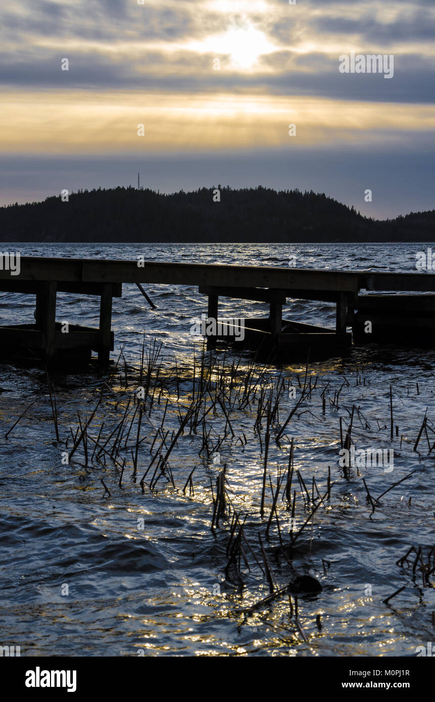 Sombre spectaculaire coucher de soleil sur jetée en bois sur le lac en Ingared près de Göteborg, Suède Banque D'Images