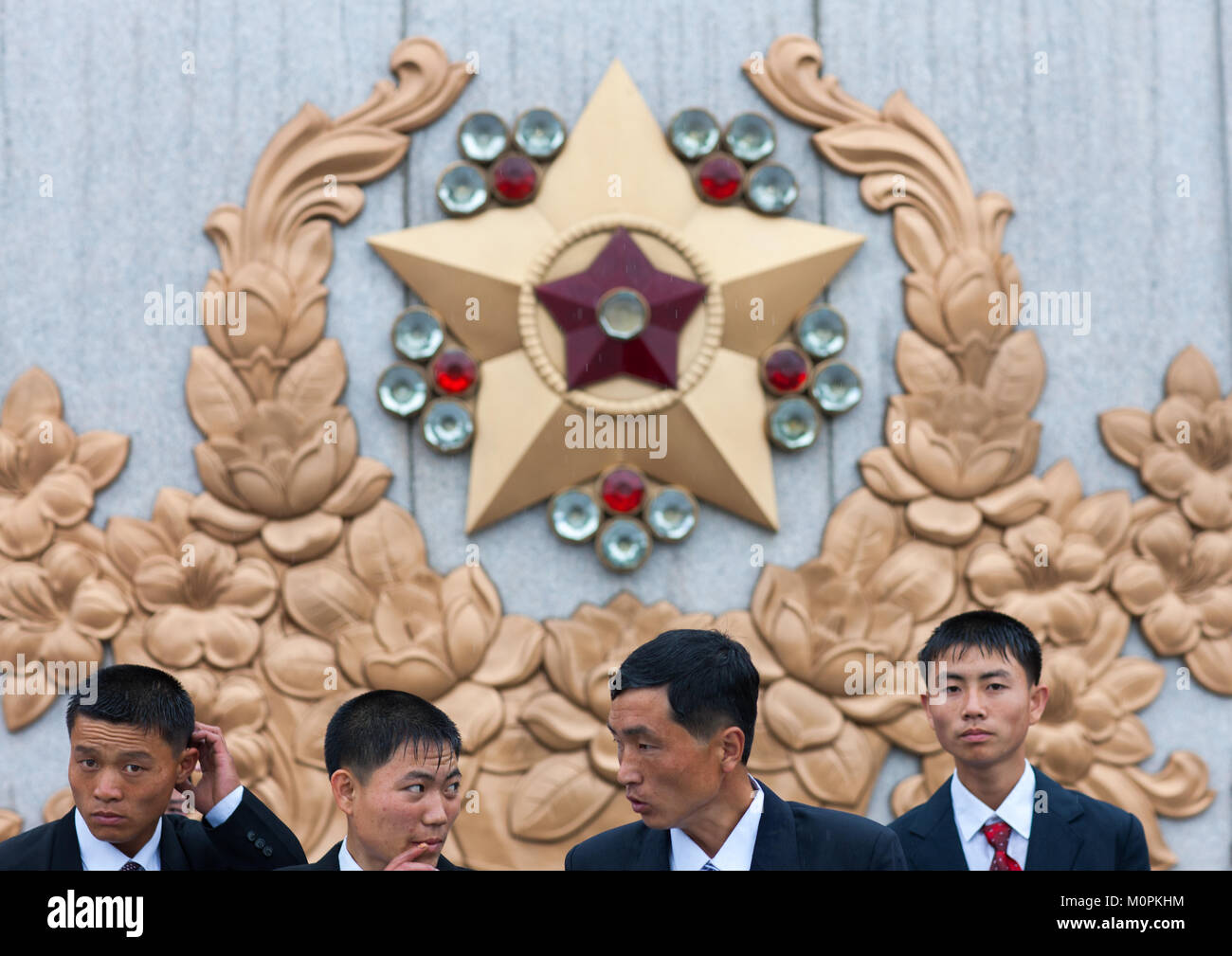 Les hommes de la Corée du Nord sous la pluie en mémorial Kumsusan palace posant devant le commandant suprême de l'Armée populaire de Corée, du logo de la province de Pyongan, Pyongyang, Corée du Nord Banque D'Images