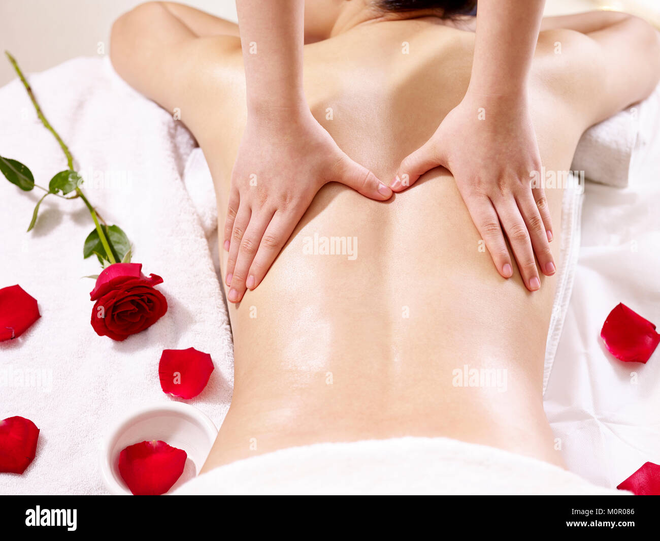Les mains d'un masseur le massage corps d'une jeune femme asiatique. Banque D'Images