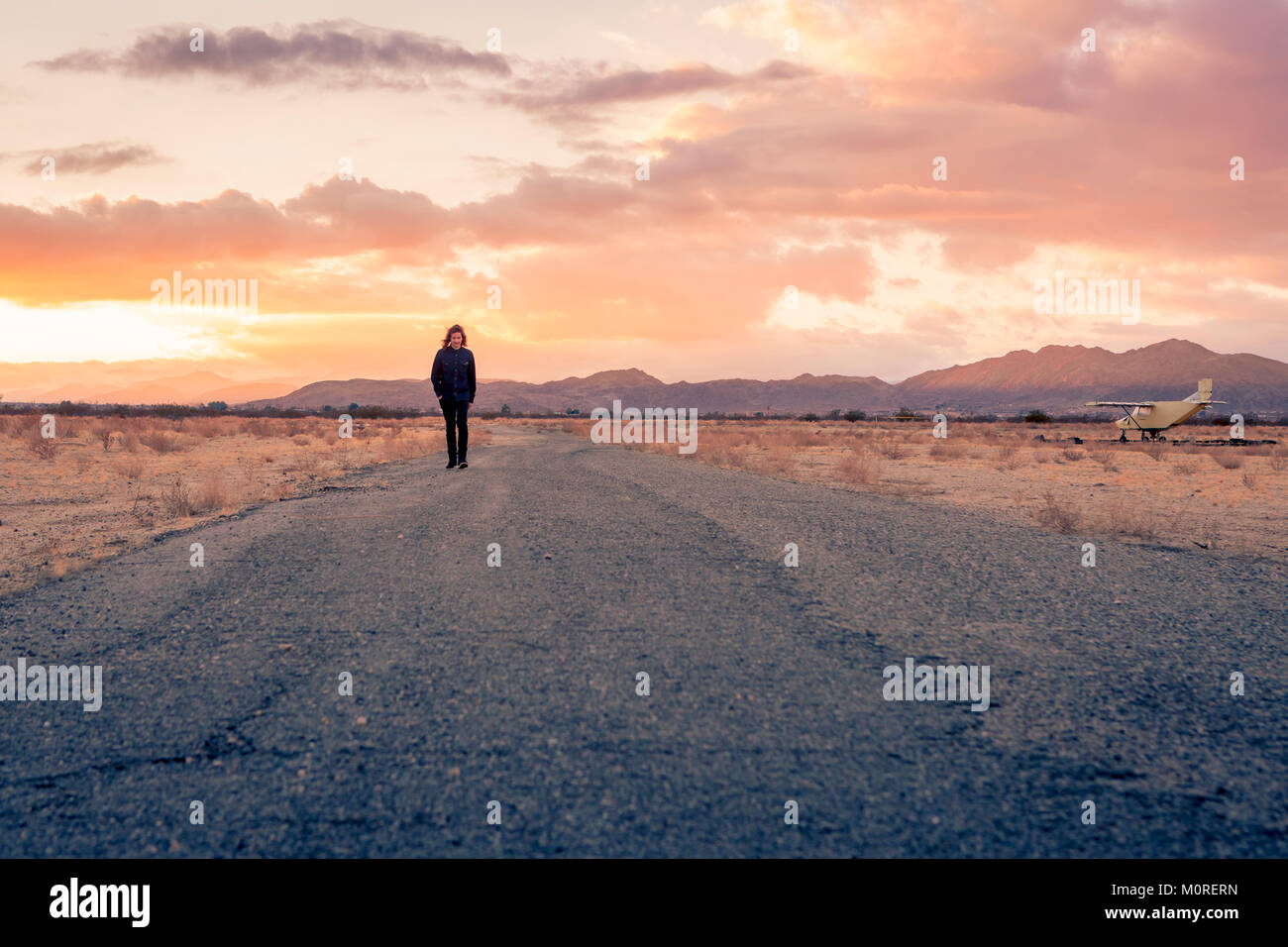 États-unis, Californie, Joshua Tree, jeune mec promenades le long d'une route alors que le coucher du soleil Banque D'Images