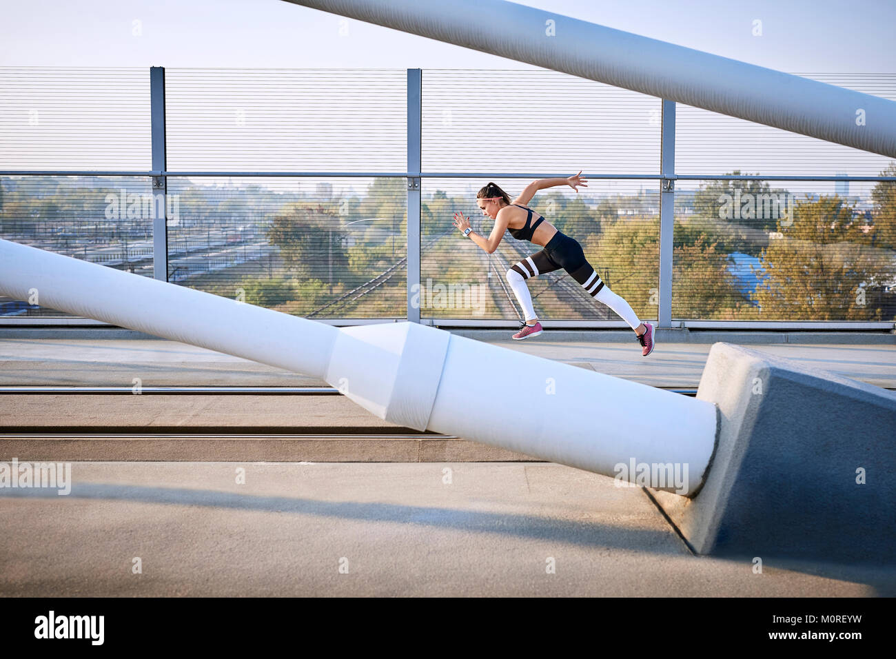 Jeune femme sprint sur un pont dans la ville Banque D'Images Jeune femme sprint sur un pont dans la ville Banque D'Images