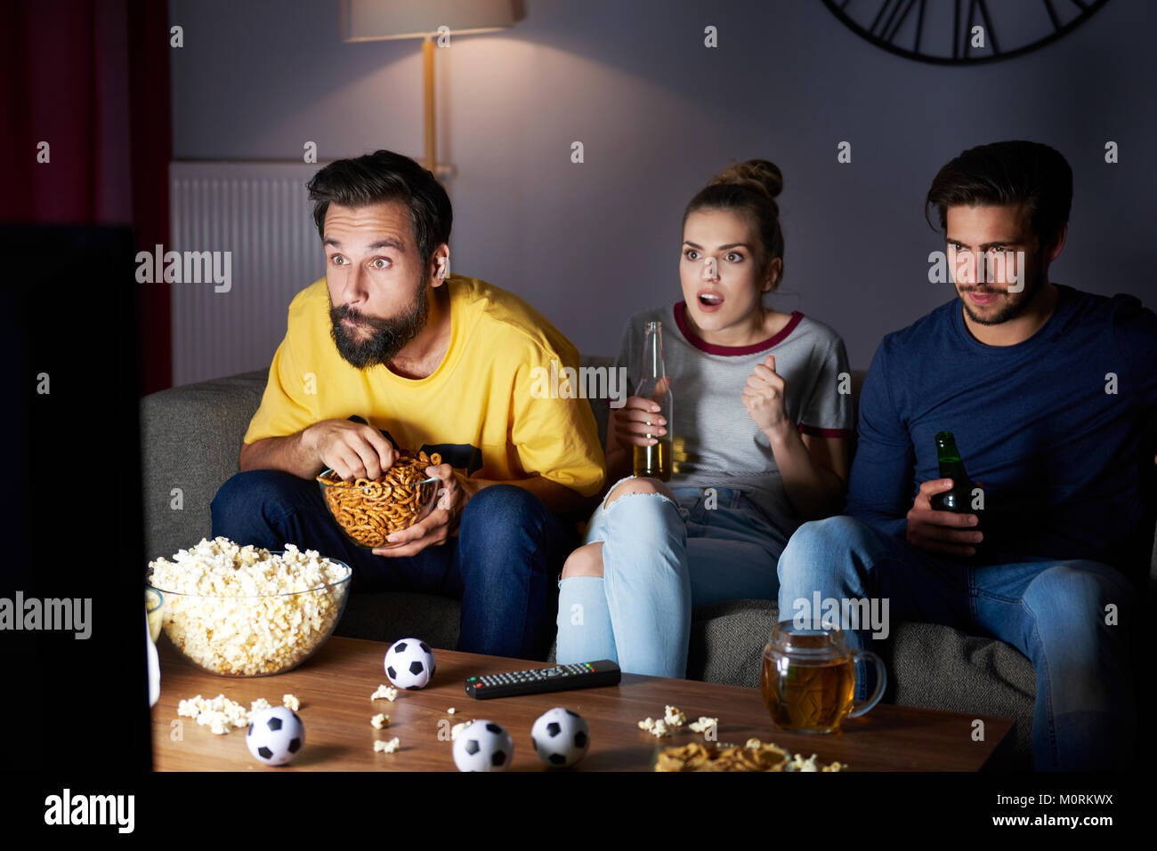 Heureux les amis assis sur le canapé en regardant la télé Banque D'Images