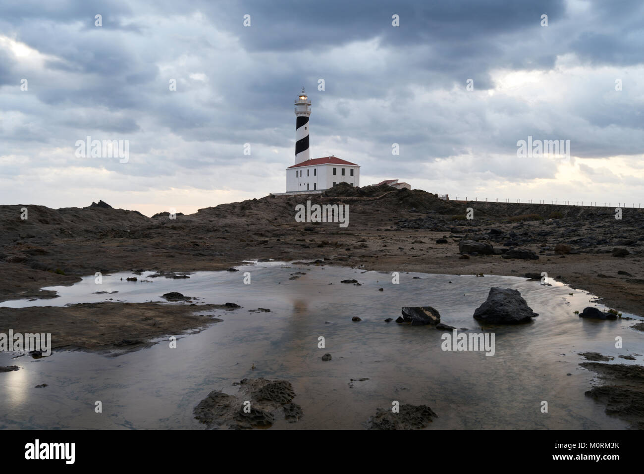 Paysage rocheux de Favaritx lighthouse dans un ciel nuageux tôt le matin au lever du soleil. Minorque, Iles Baléares, Espagne. Banque D'Images