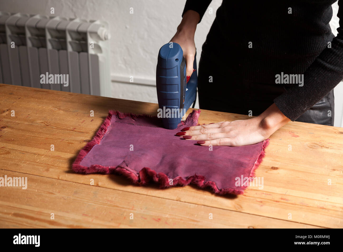 Le processus de création d'un manteau de fourrure femme. Un gros plan d'une jeune femme fourreur sèche une machine spéciale avec fourrure naturelle pour faire une femme de manteau de fourrure. Banque D'Images