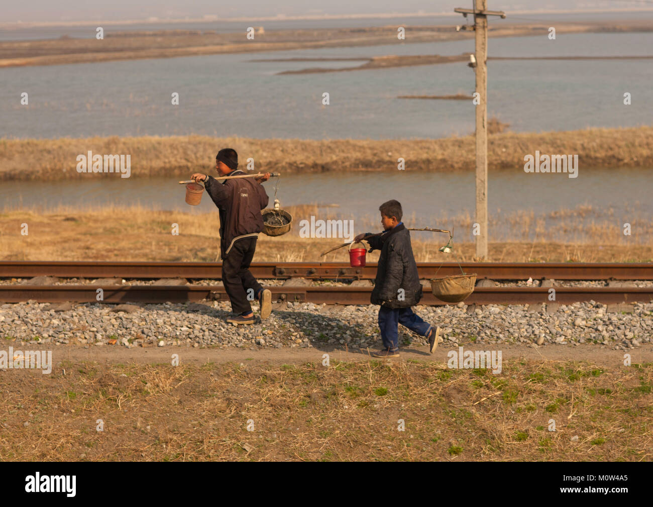 Les garçons nord-coréen transportant de la nourriture dans des paniers le long d'un chemin de fer, de la province de Pyongan, Pyongyang, Corée du Nord Banque D'Images