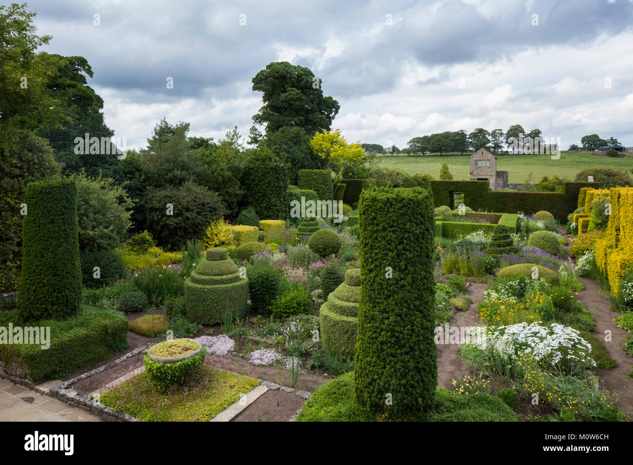 Une vue surélevée sur le jardin fleuri de Herterton House avec le grand gazebo en pierre en arrière-plan et la campagne au-delà, Northumberland, Angleterre. Banque D'Images