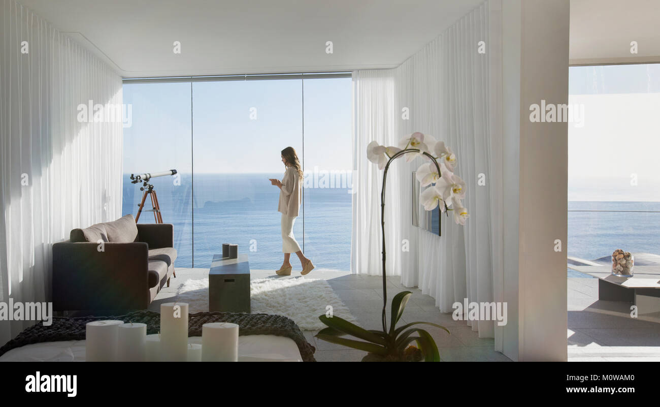 Femme debout sur un luxe moderne home vitrine balcon ensoleillé avec vue sur l'océan Banque D'Images