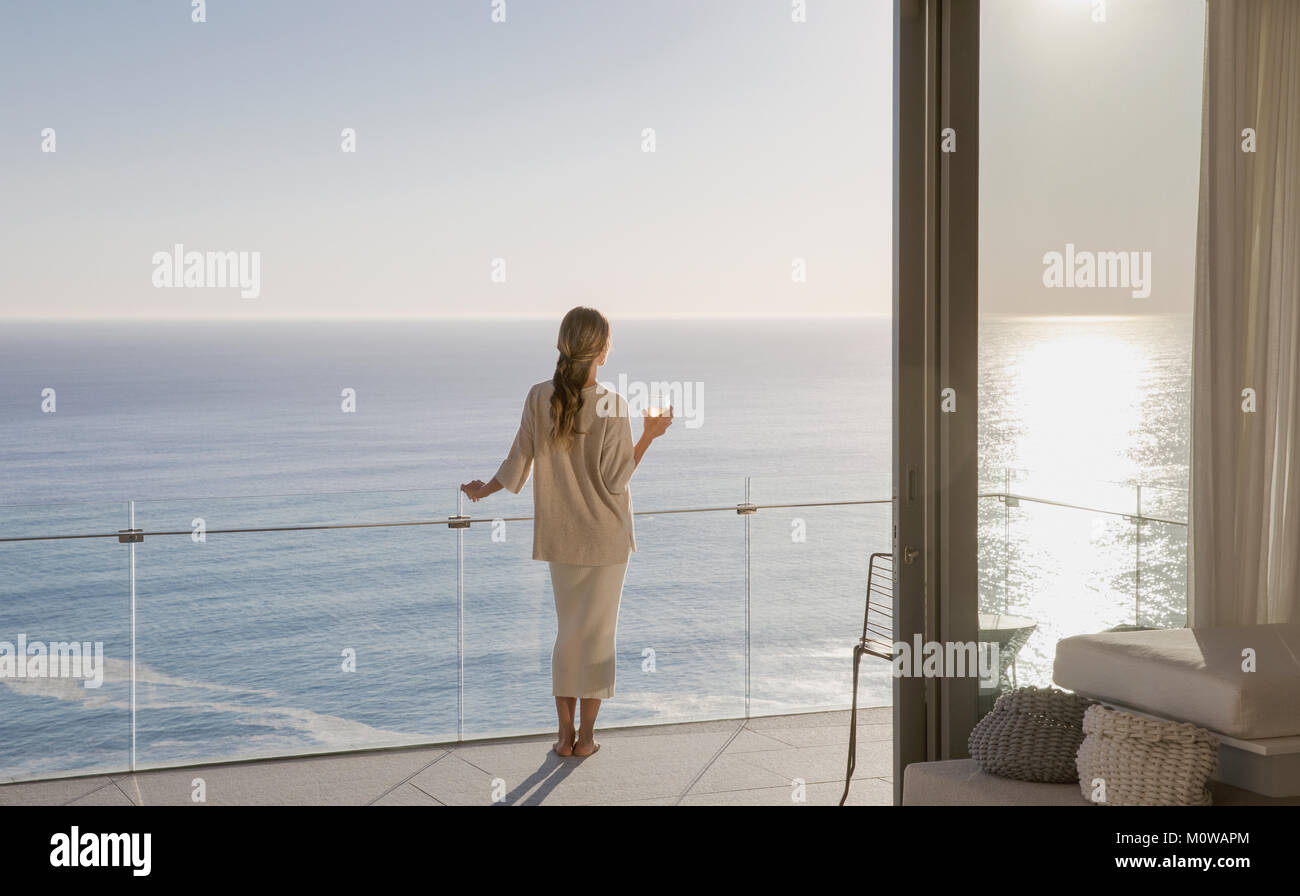 Femme debout sur luxe ensoleillé balcon avec vue sur l'océan Banque D'Images