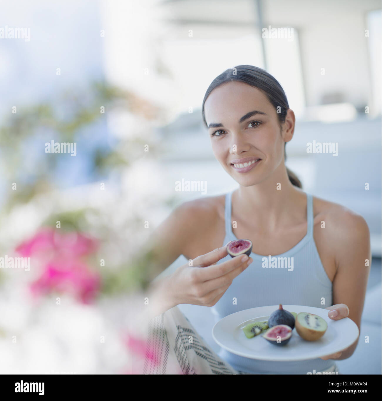 Portrait of smiling brunette woman eating figs et kiwi Banque D'Images