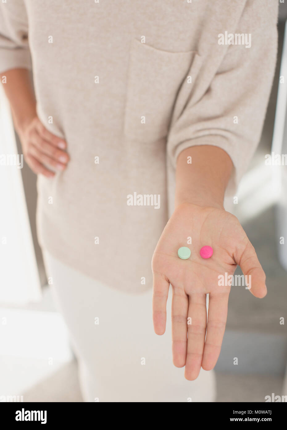 Woman holding, montrant deux pilules, rose et vert Banque D'Images